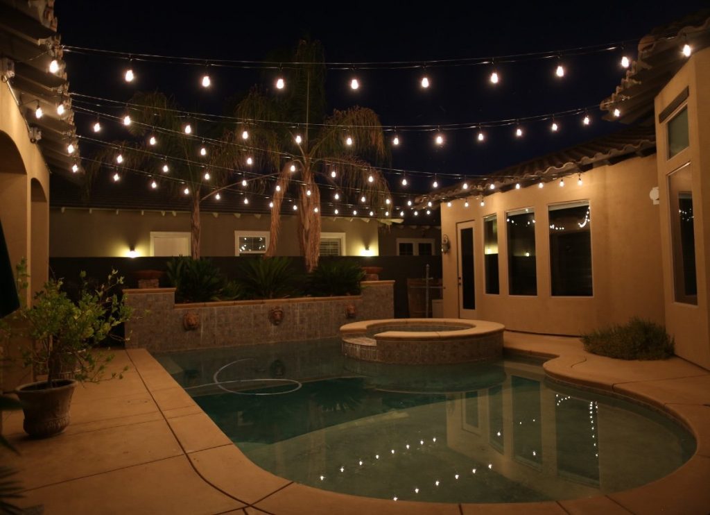 A set of solar-powered string lights provides some warmth and ambiance to a pool area.