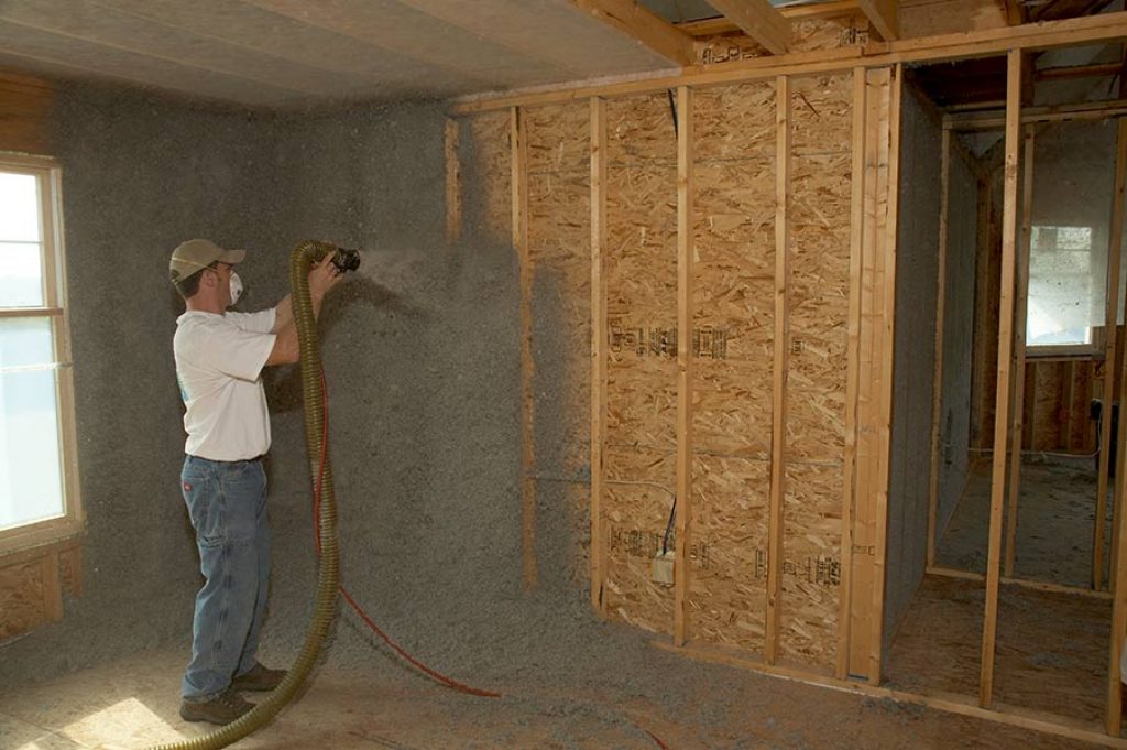 Green fiber insulation being applied to a wall.