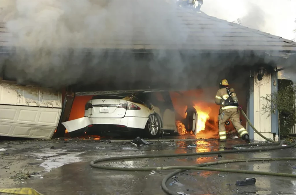 A firefighter tries to put out the fire from a burning Tesla after it crashed into a garage in California, in 2017. Firefighters identified the fuel source as the EV's high-voltage battery pack.