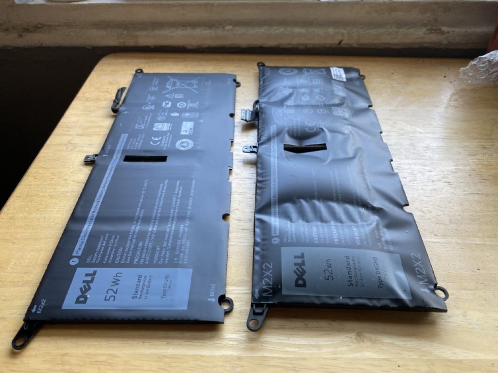 The image shows two laptop li-ion batteries side by side: the one on the left is in normal conditions and the one on the right is swollen/damaged.