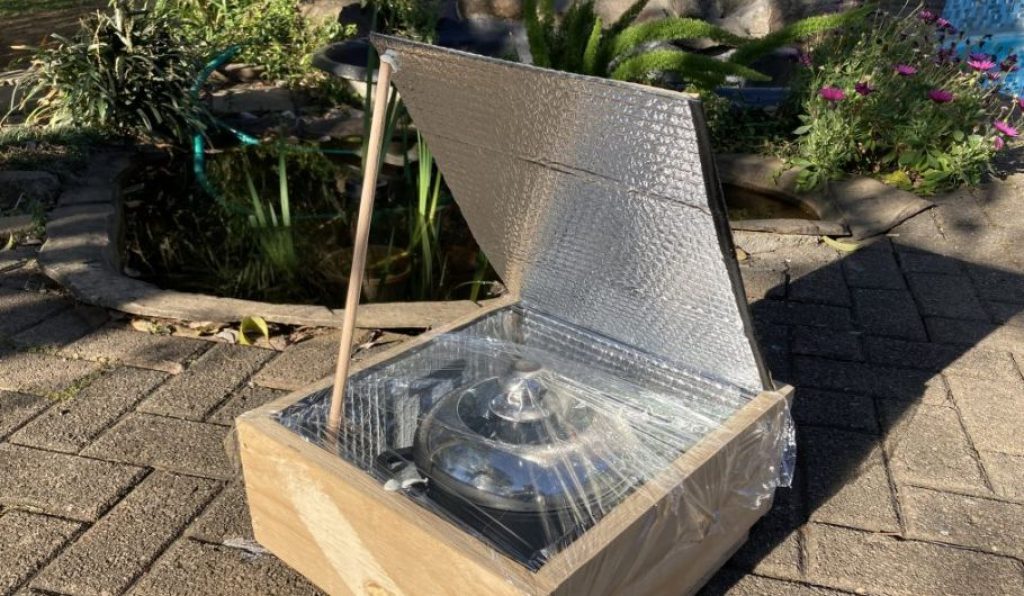The complete solar cooker with plastic wrap and a pot inside. 