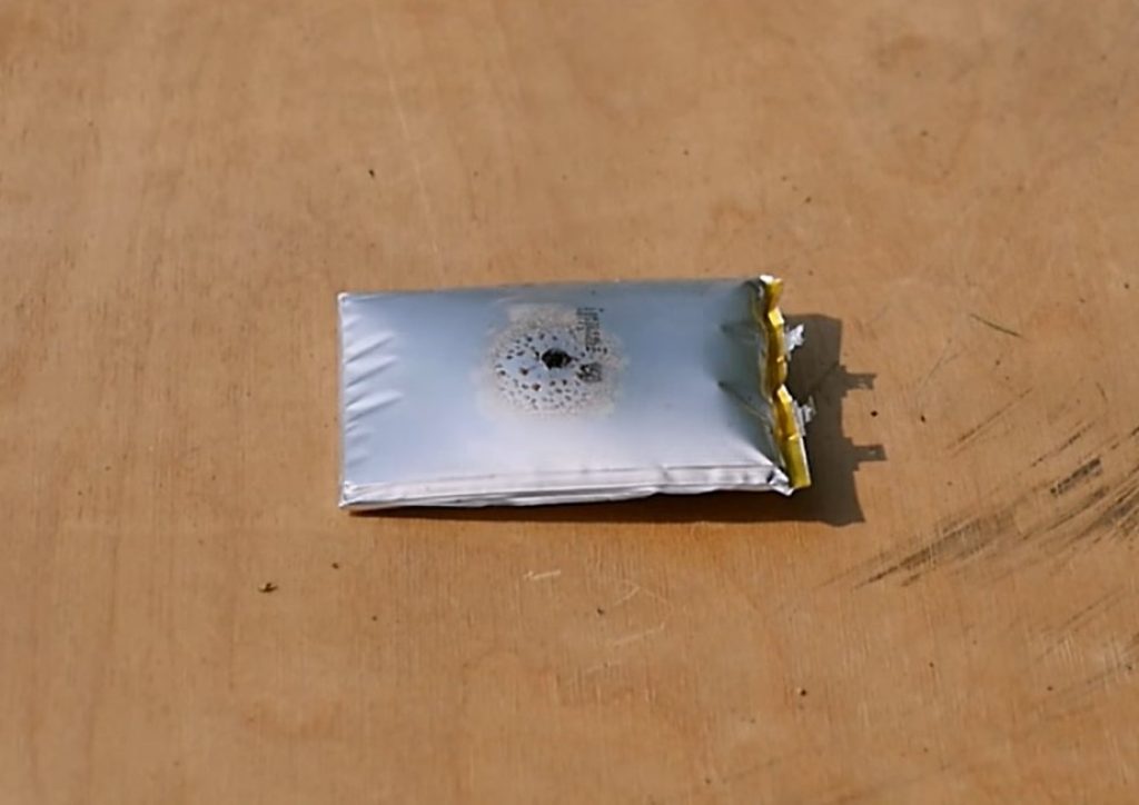 The image shows a punctured swollen lithium battery. 