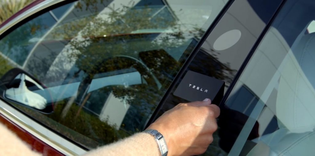 A Tesla key card held up against the driver door pillar. 