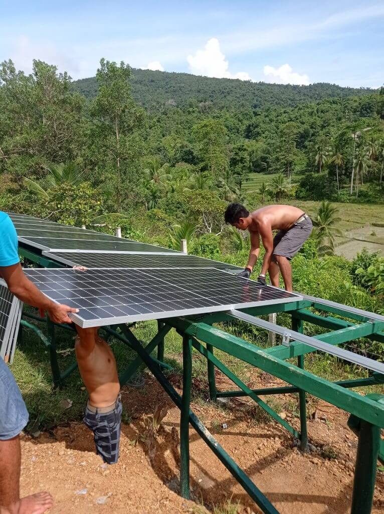 Placing solar panels on ground-mounted array. Designed and overseen by Romain Metaye, author at Climatebiz.