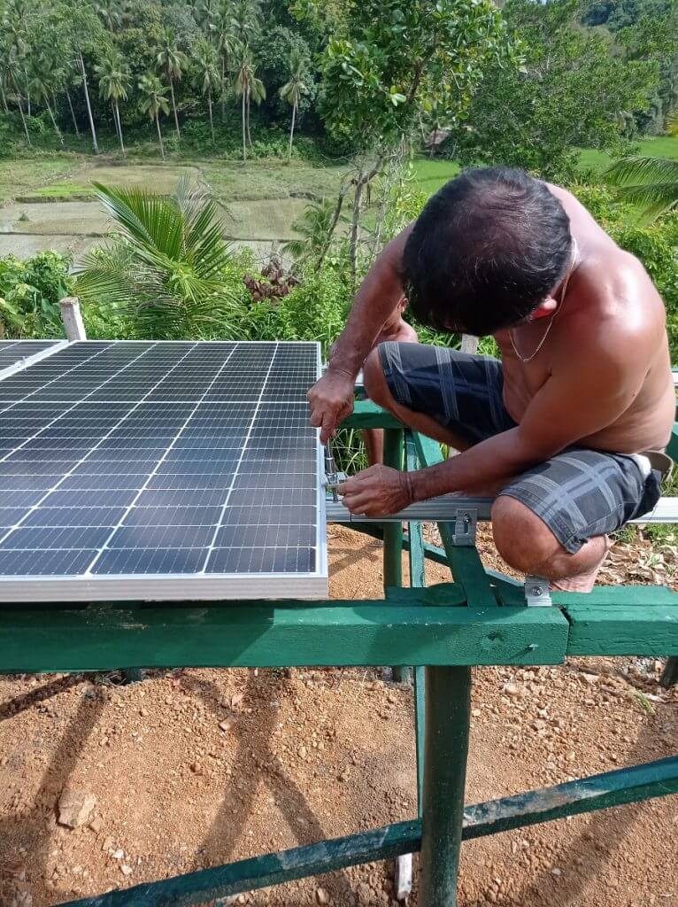 Placing solar panels on ground-mounted array. Designed and overseen by Romain Metaye, author at Climatebiz.